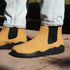 Yellow boots with black soles worn by a person on a concrete surface.