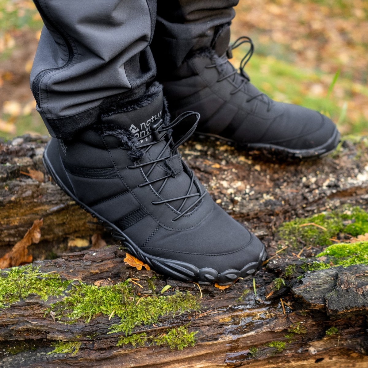 Black winter barefoot boots on a log with a natural background