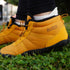 Naturcontact Arctic 4.0 gold winter barefoot boots with warm lining shown outdoors on grass, highlighting flexible sole and lightweight minimalist design.
