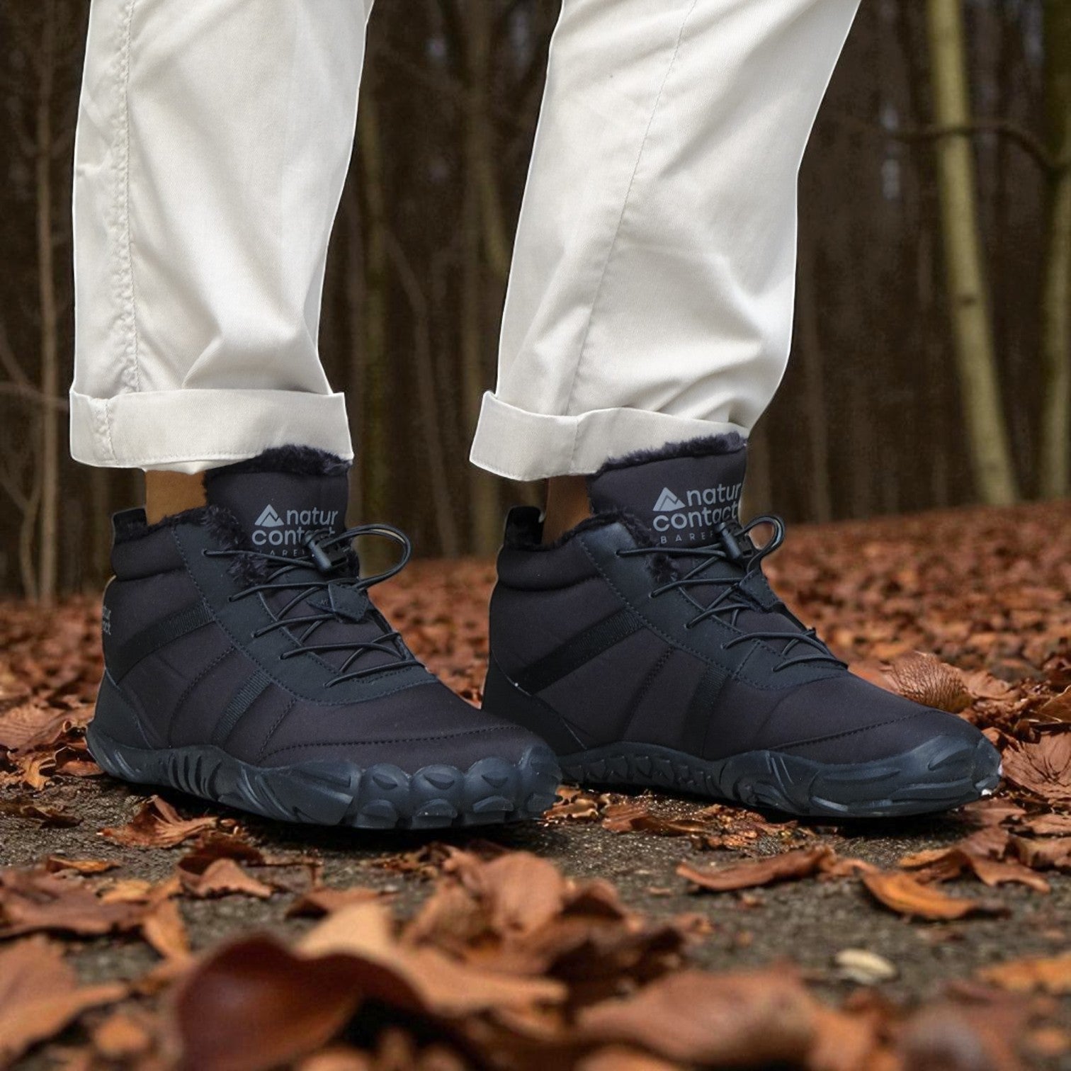 Navy hiking boots with visible brand logo worn on a forest floor.