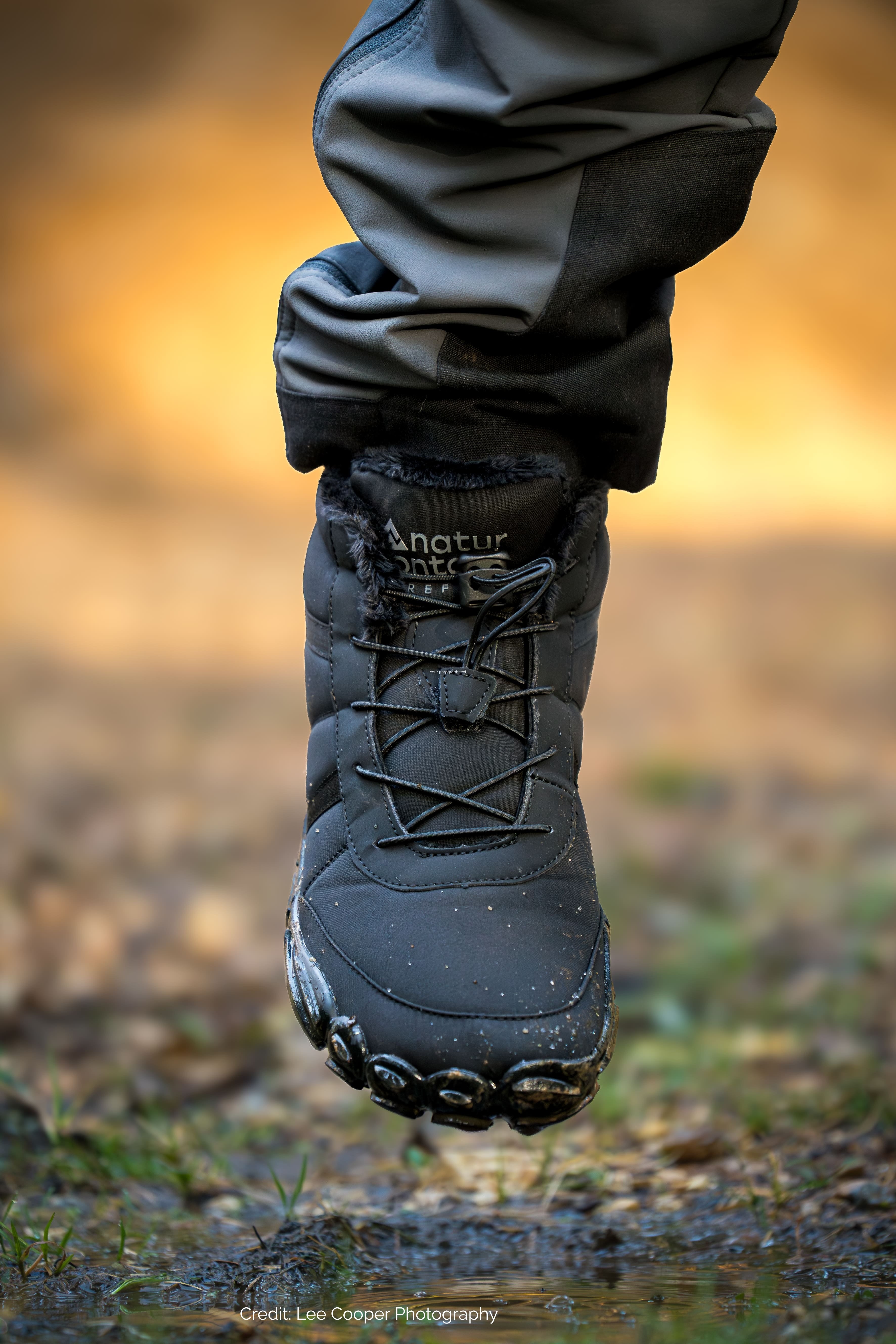 Black hiking barefoot boot with brand name naturcontact on a blurred natural background