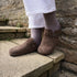 Close-up of brown suede clogs worn with thick grey socks on stone steps.