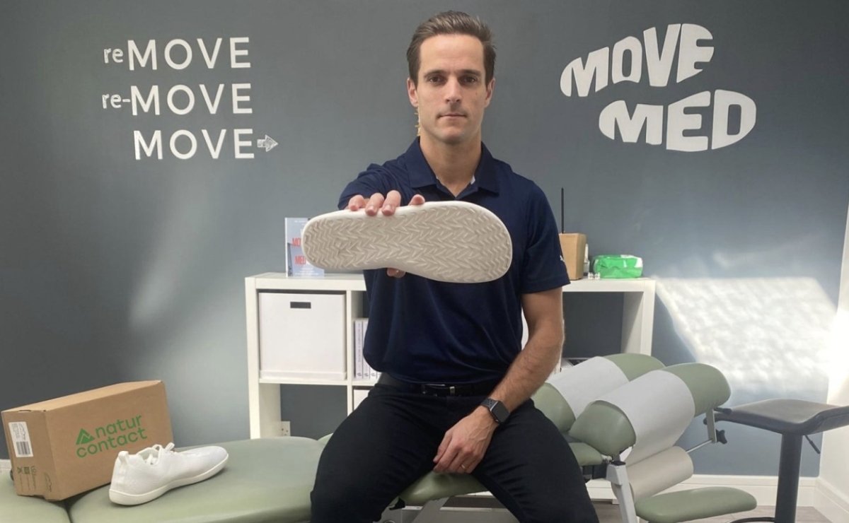 podiatrist holding naturcontact shoes insert in a doctor room with 'MOVE MED' branding.
