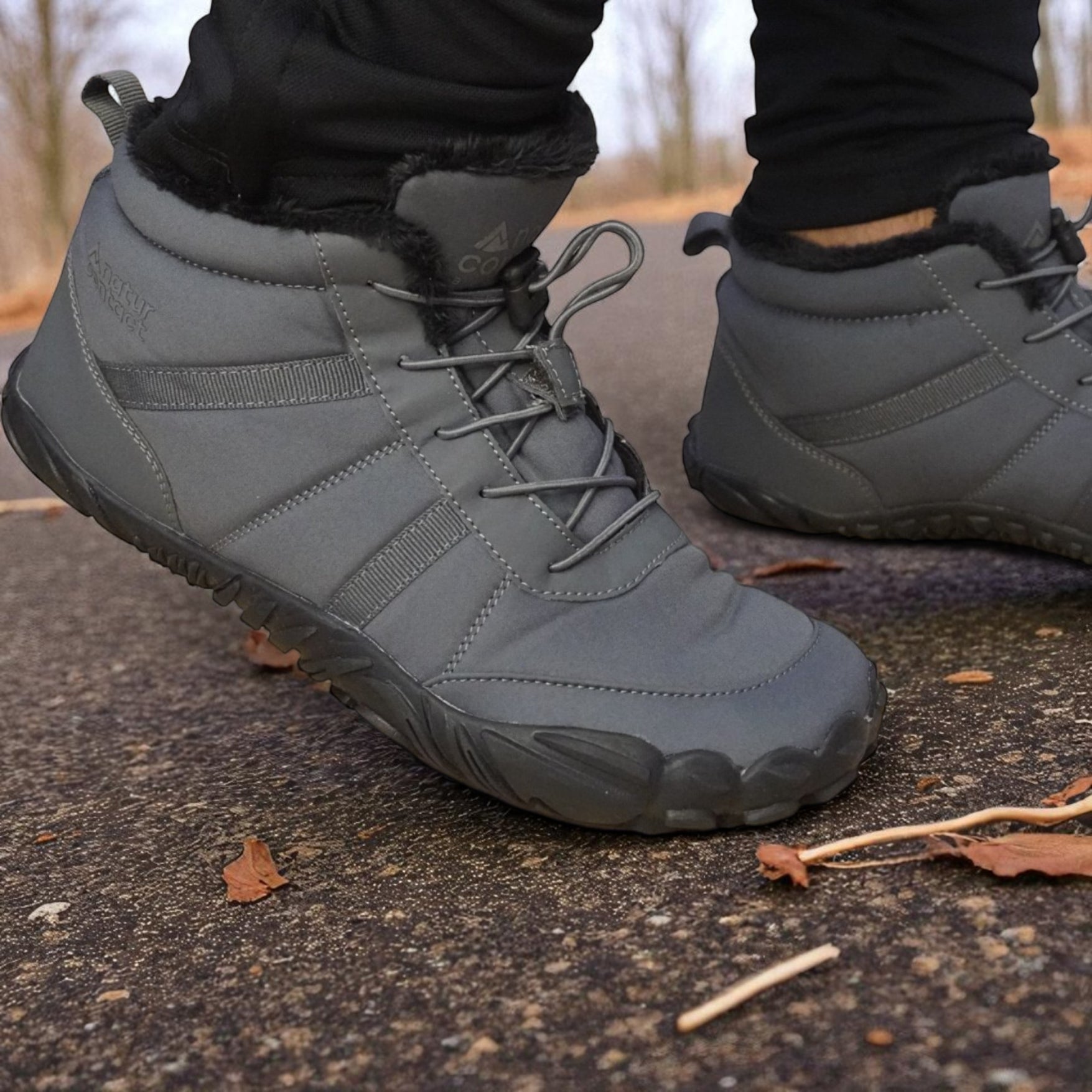 Gray winter boots with fur lining worn on a concrete surface.