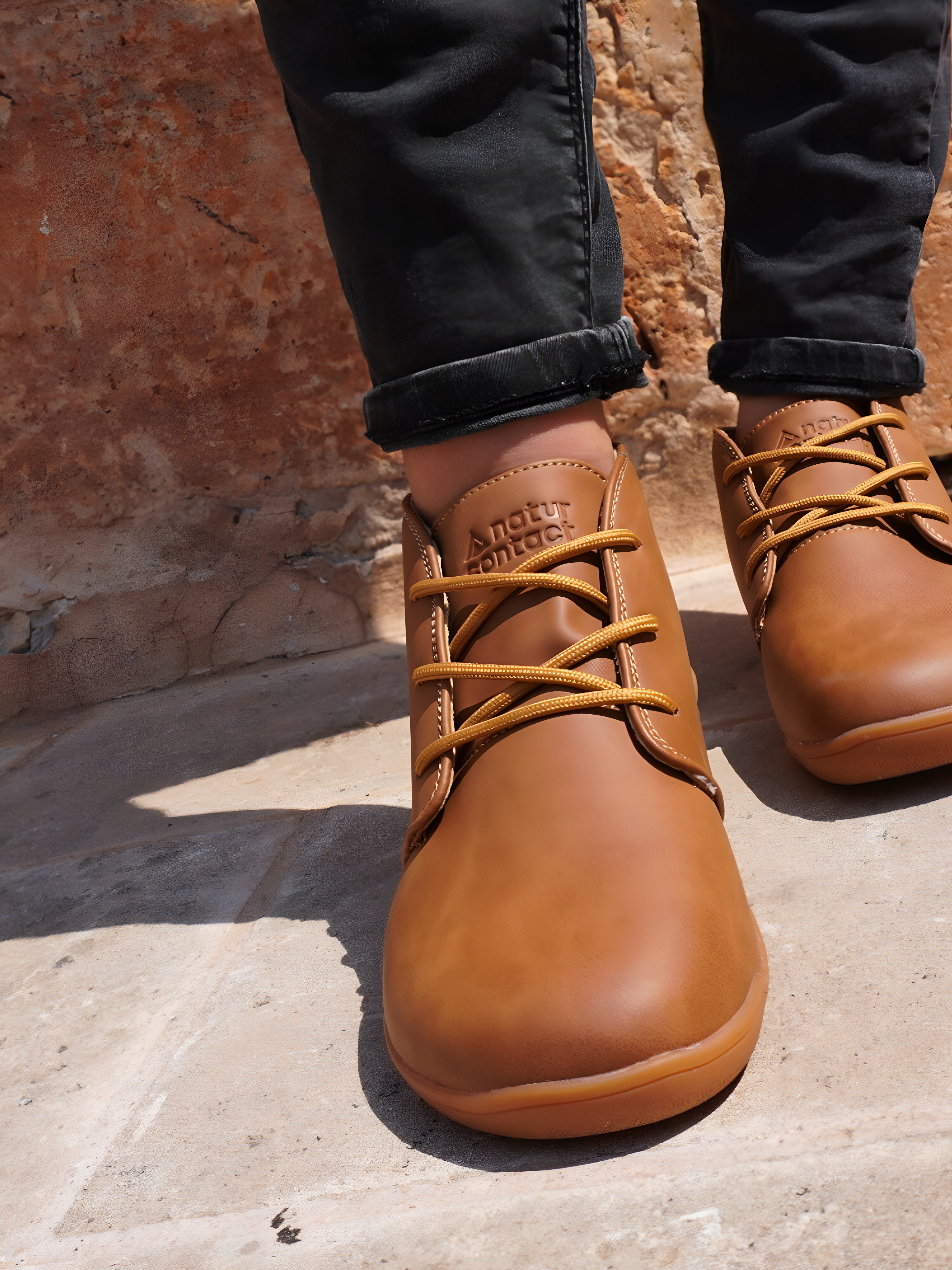 Brown leather shoes with laces worn on a stone surface.