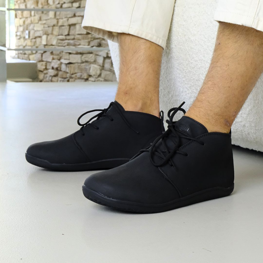 Black George barefoot shoes worn by a person in office background 
