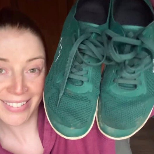 Person holding up a pair of green aramid naturcontact barefoot shoes  sneakers