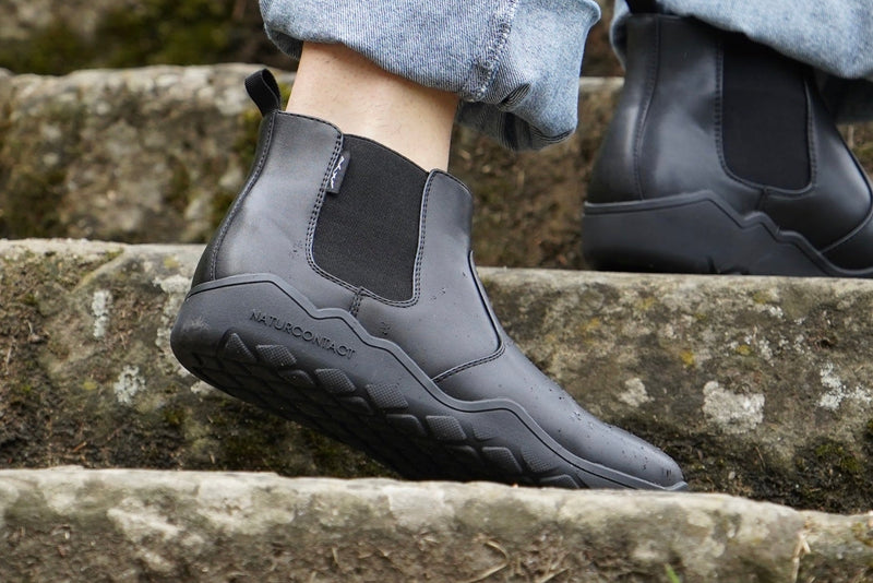 Person wearing black Chelsea boots on stone steps