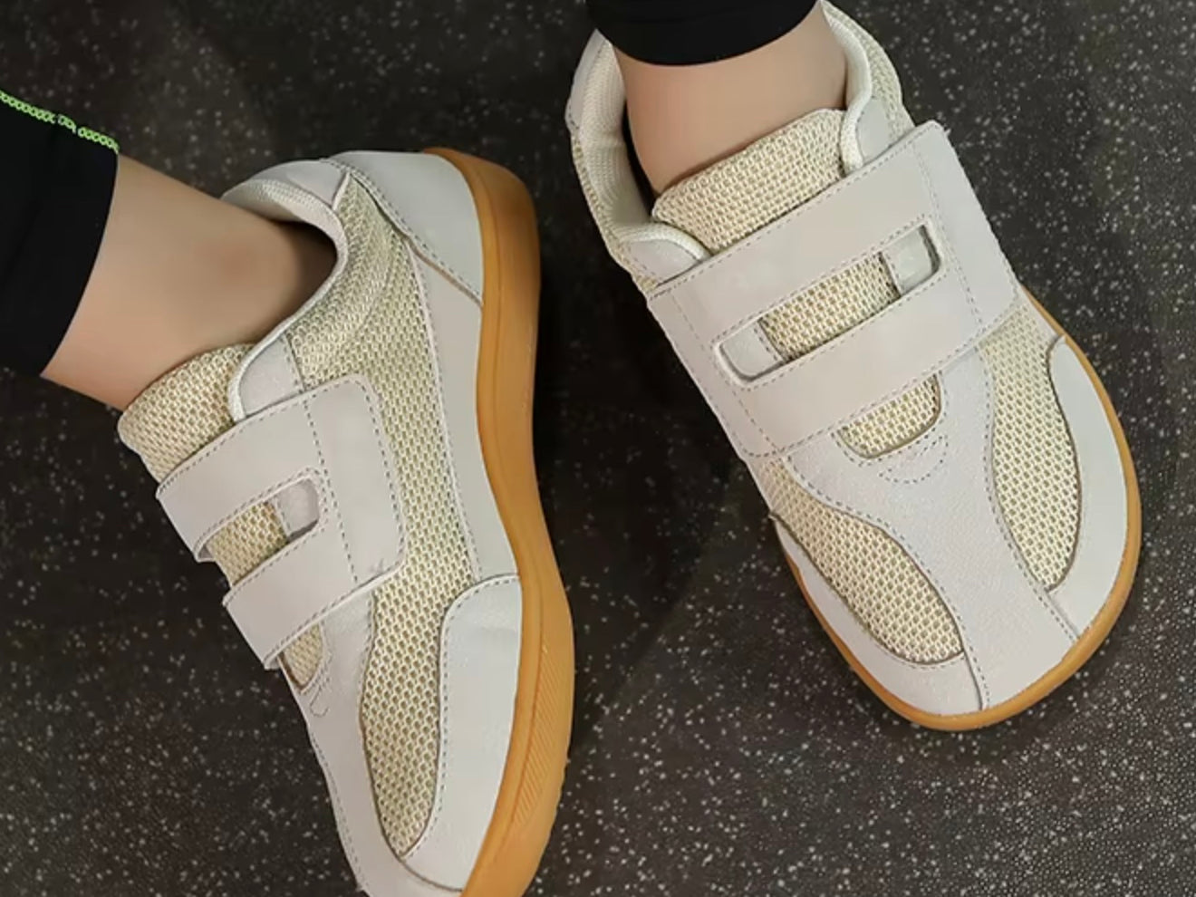 White sneakers with brown soles on a dark textured surface