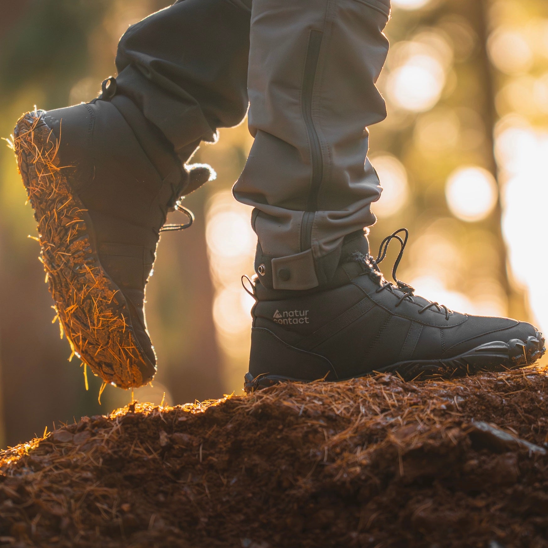 Person wearing black hiking boots with natural sole on a forest floor