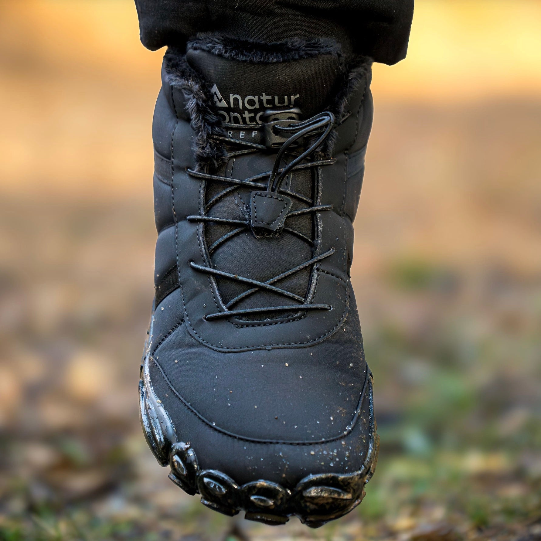 Black hiking boot with brand name on a blurred natural background