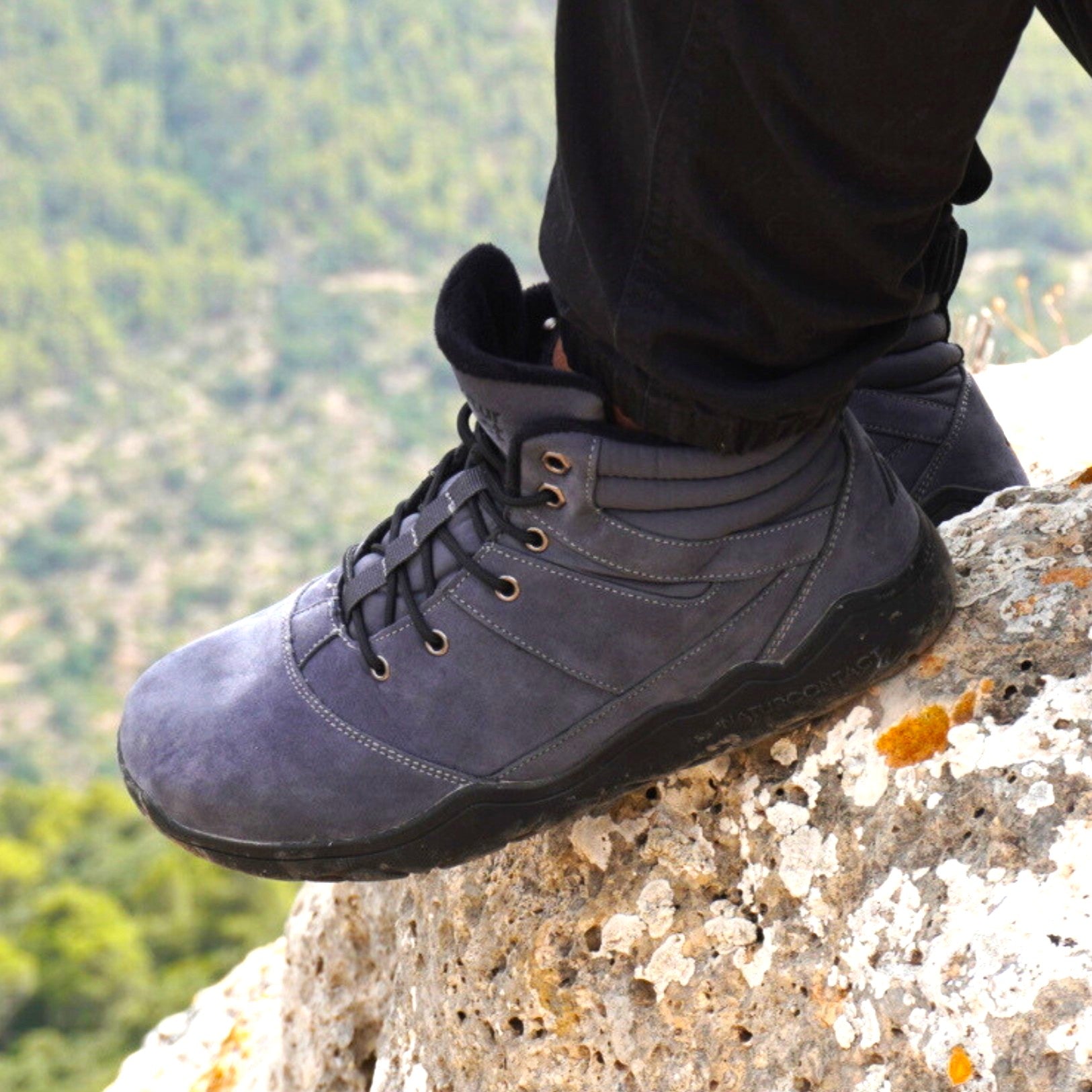 Gray hiking barefoot boot on a rocky outcrop with a blurred natural background