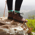 Person wearing brown hiking barefoot boots and colorful socks standing on a rock with a scenic background