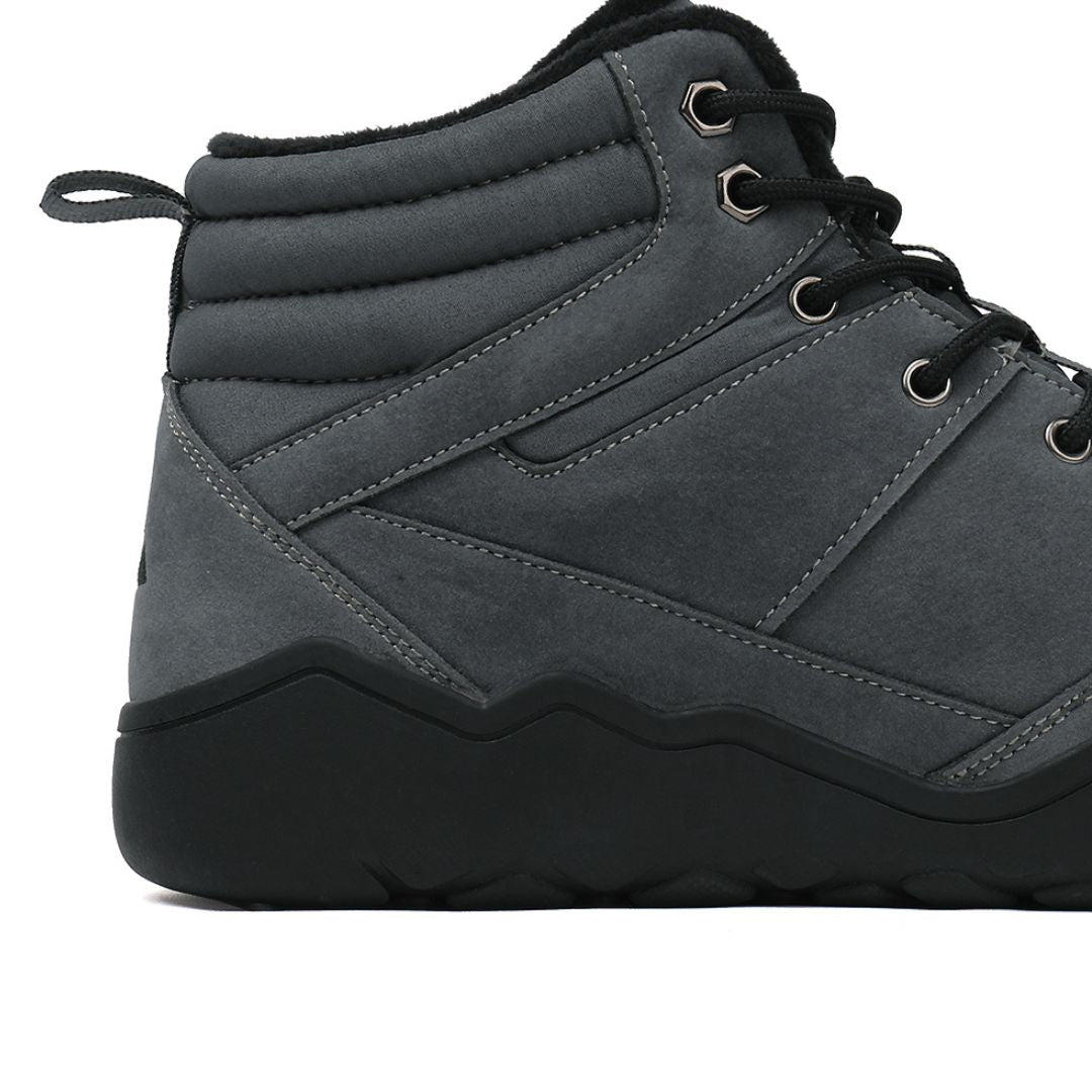 Grey winter barefoot shoe with black laces on a white background, close-up side view.
