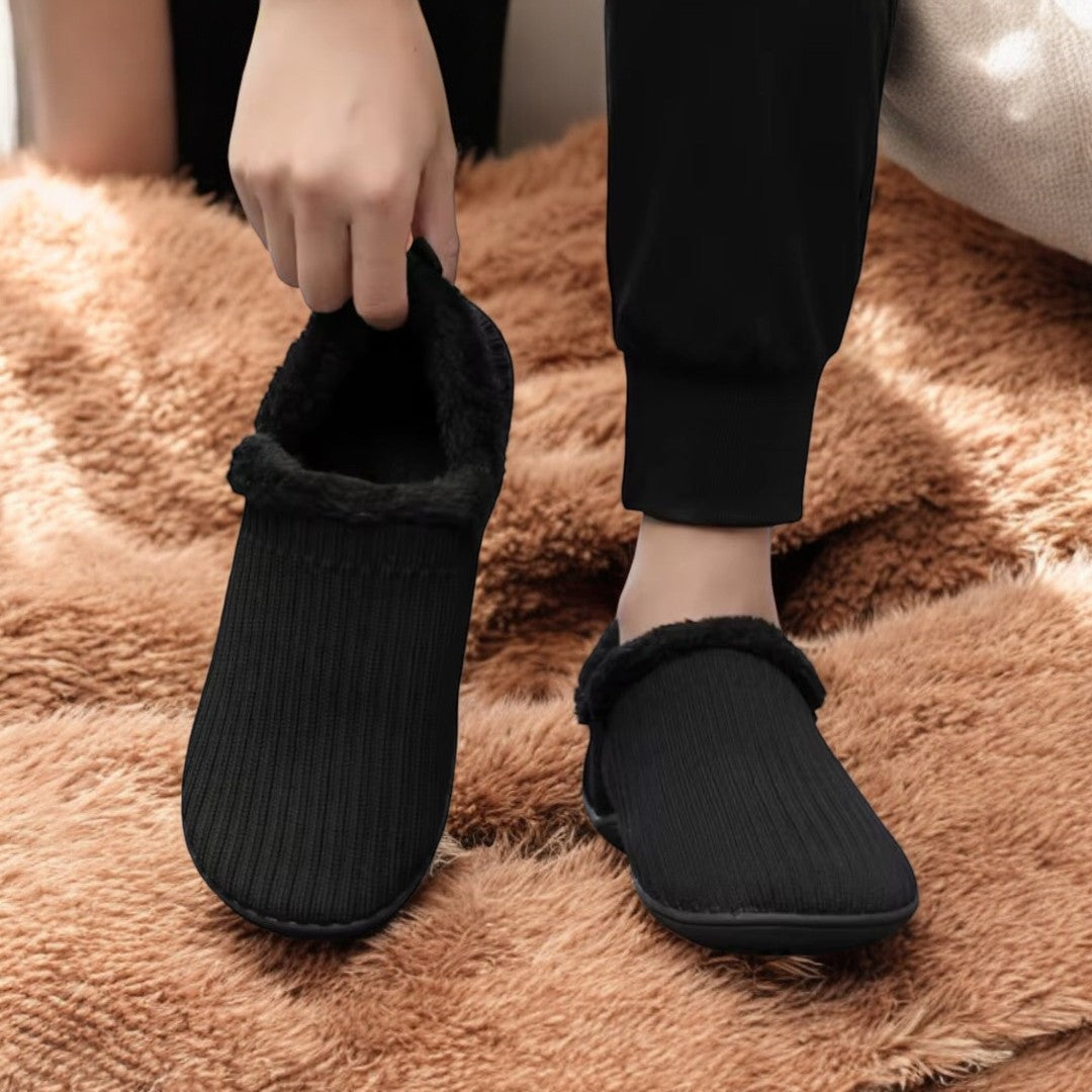Person wearing black slippers on a fluffy brown carpet