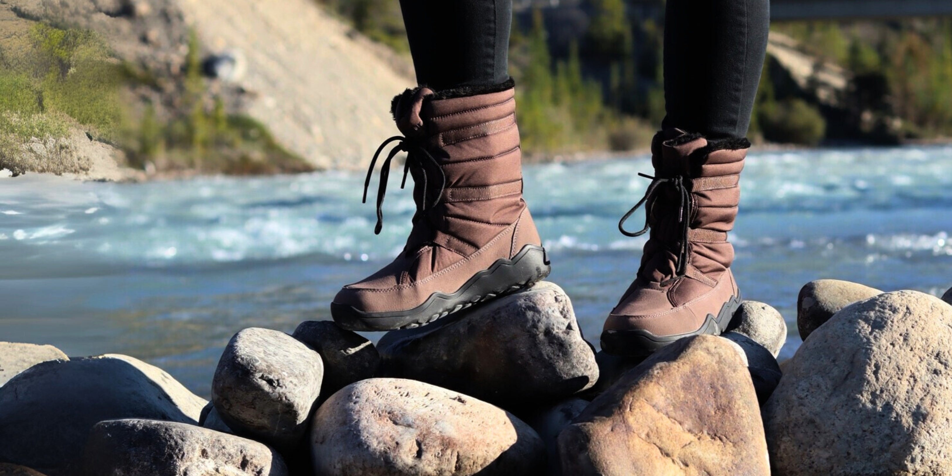 Brown boots on rocks with a scenic background