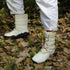 White winter boots with brown laces worn on a leaf-covered ground