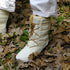 White winter boots with brown laces on a leaf-covered ground