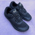 Pair of black athletic shoes with 'naturcontact' branding on a light purple surface.