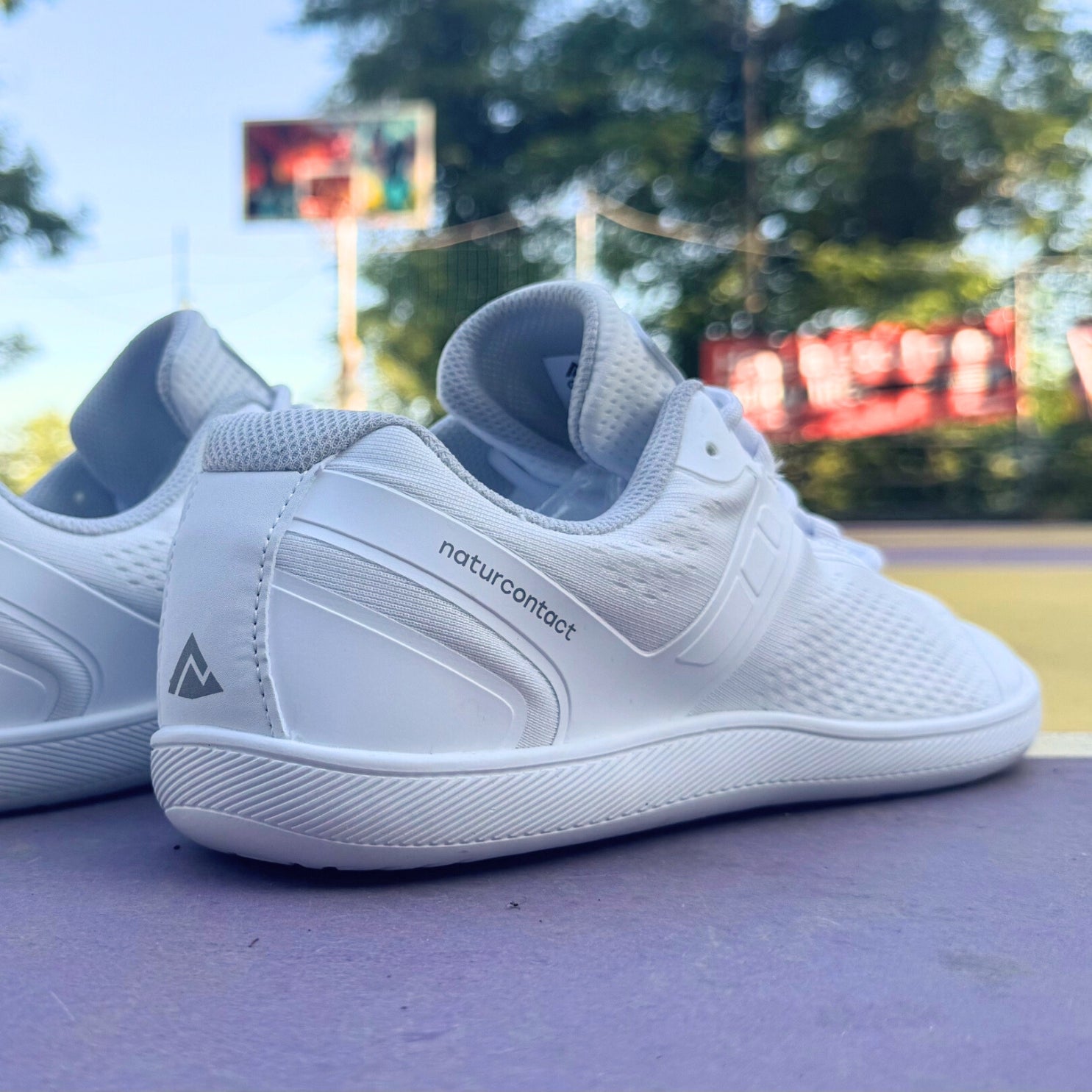 White sneakers with 'naturcontact' branding on a blurred outdoor background