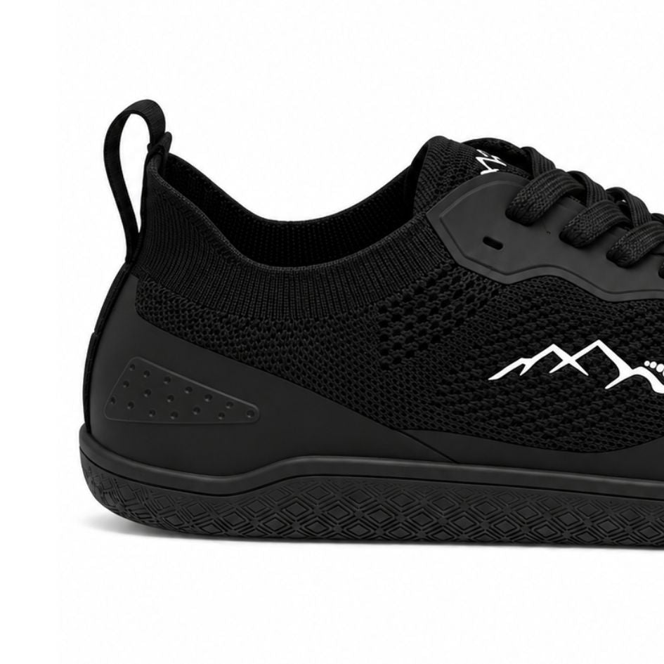Close-up of black Naturcontact Aramid Contact 2.0 barefoot trainers showing the black laces, tongue emblem and breathable knitted fabric.