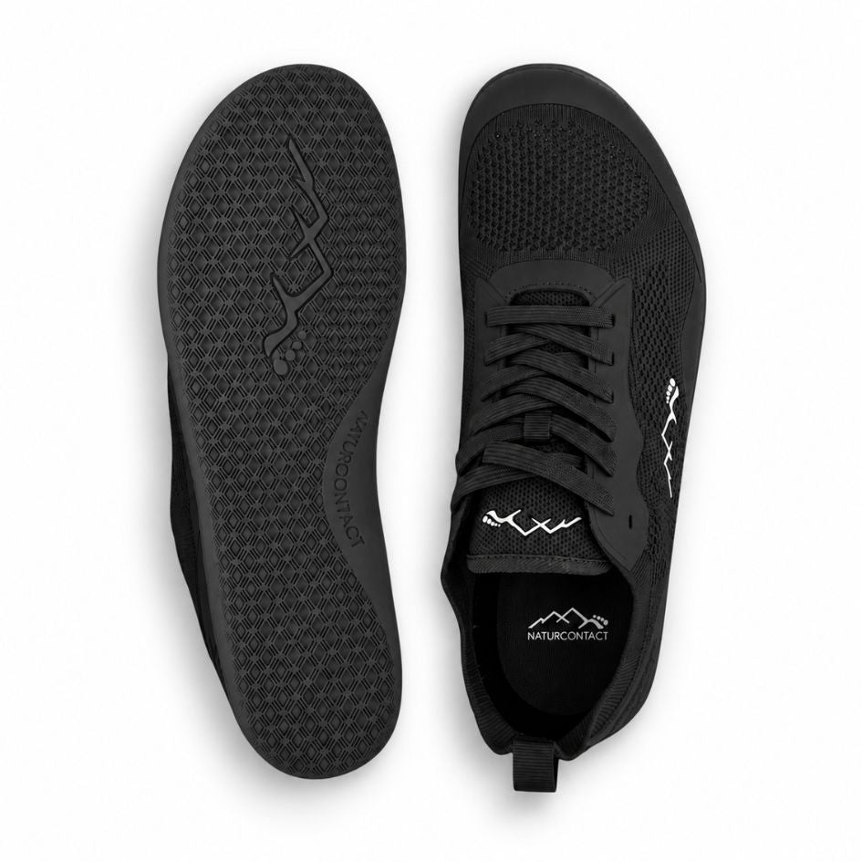 Top and outsole views of black Aramid Contact 2.0 barefoot shoes showing the lace-up upper and textured black tread pattern.