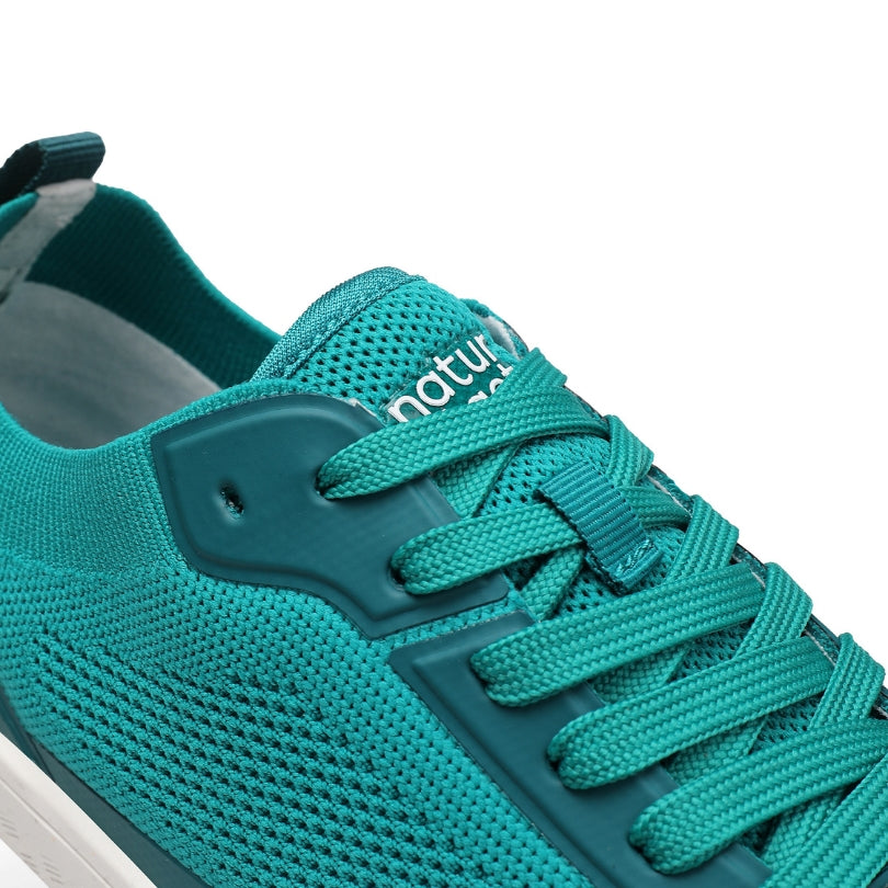 detail of Teal barefoot athletic shoe with brand logo on a white background