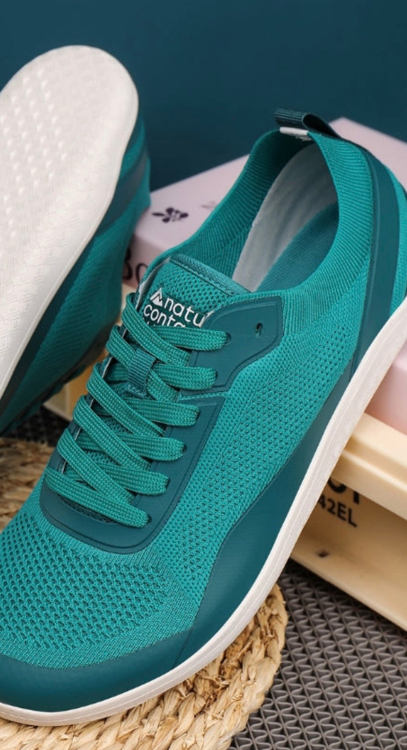 Teal barefoot shoes with white sole on a textured surface