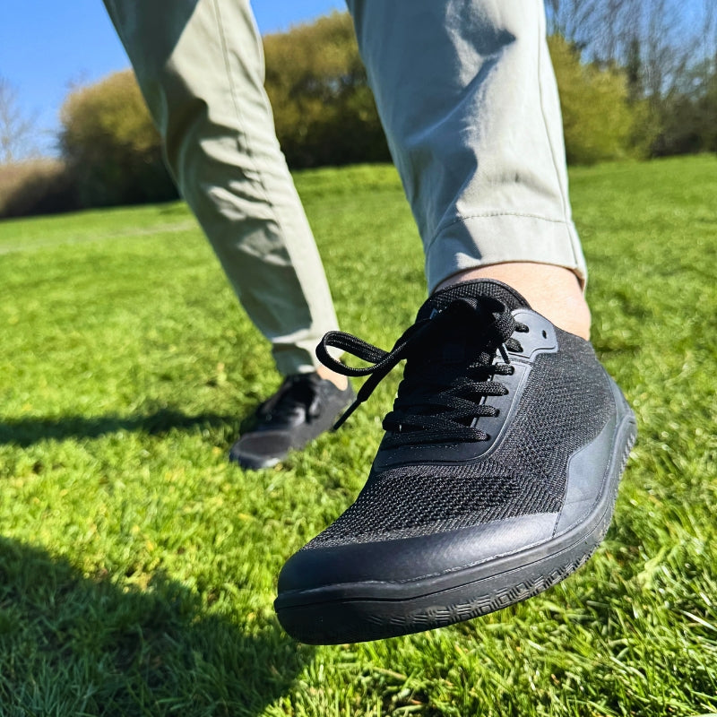 utdoor exercise featuring Naturcontact black athletic barefoot shoes on grass.