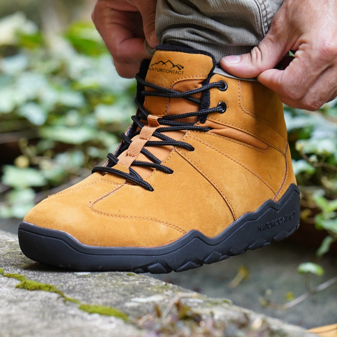 Naturcontact Intemperia winter barefoot boots in Gold suede, worn outdoors on natural terrain, featuring zero drop sole, wide toe box and flexible minimalist design for winter use.