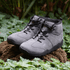 Pair of Naturcontact Intemperia winter barefoot boots in Grey, featuring a wide toe box, flexible sole and suede upper, displayed outdoors on natural terrain.
