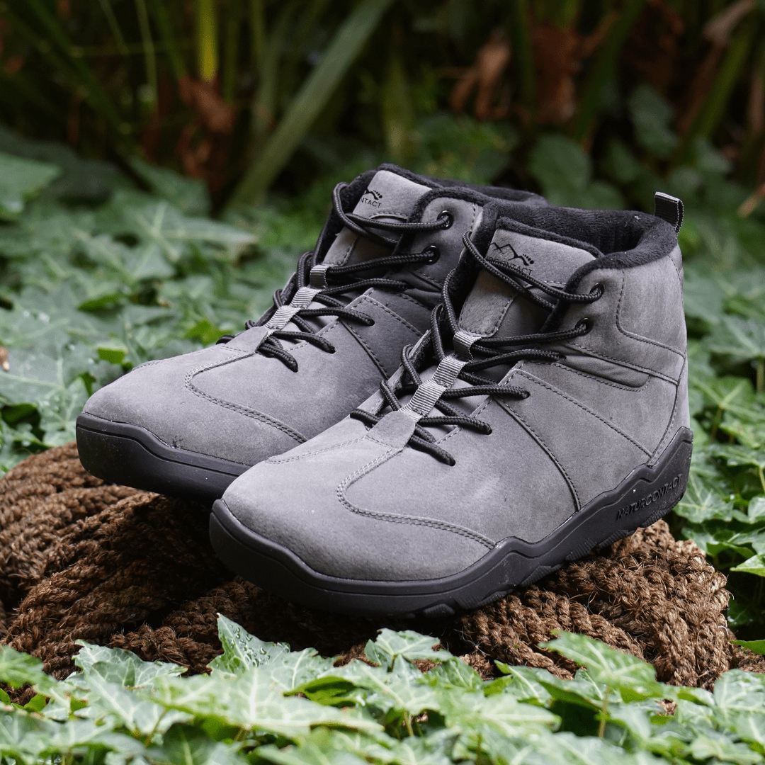 Pair of Naturcontact Intemperia winter barefoot boots in Grey, featuring a wide toe box, flexible sole and suede upper, displayed outdoors on natural terrain.
