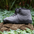 Pair of Naturcontact Intemperia winter barefoot boots in Grey, featuring a wide toe box, flexible barefoot sole and suede upper, displayed outdoors on a natural rope surface surrounded by greenery.