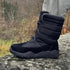 Black Naturcontact Lapland high-top winter barefoot boots worn outdoors on rocky terrain, showing flexible sole and insulated design