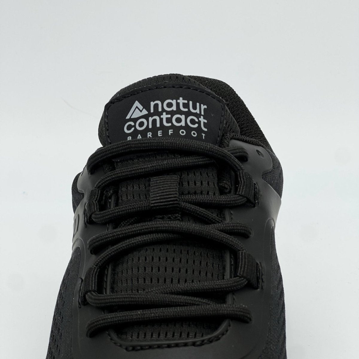 Close-up front view of black Naturcontact Metro Flex 3.0 barefoot shoe showing laces, tongue logo and breathable mesh upper on white background