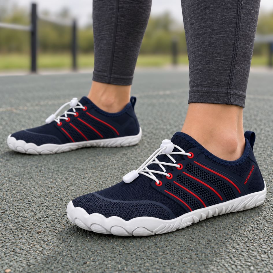Navy blue and red Naturcontact Sport Contact 2.0 barefoot trainers worn with dark leggings outdoors, showing the flexible low-profile design.