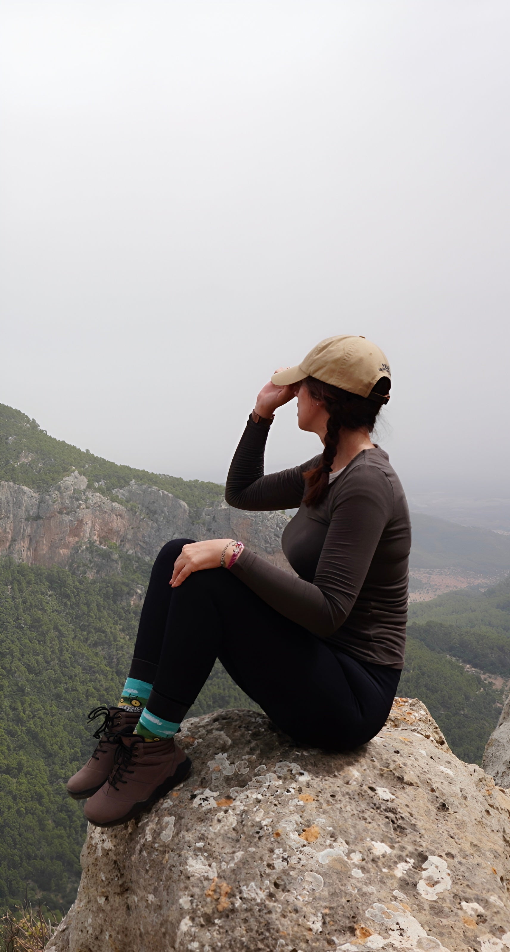 Person sitting on a rock with mountains in the background