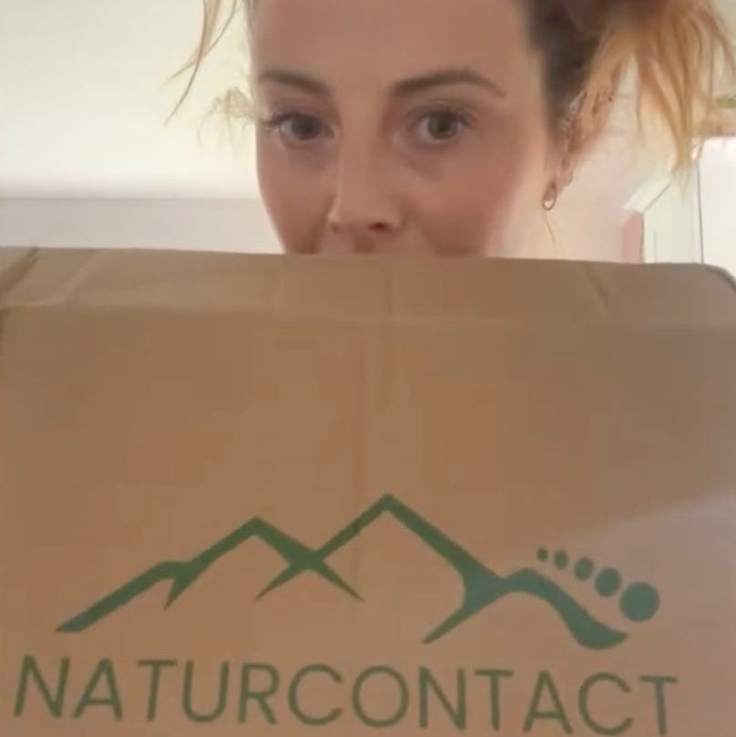 Person peeking over a cardboard box with a logo and text on it.