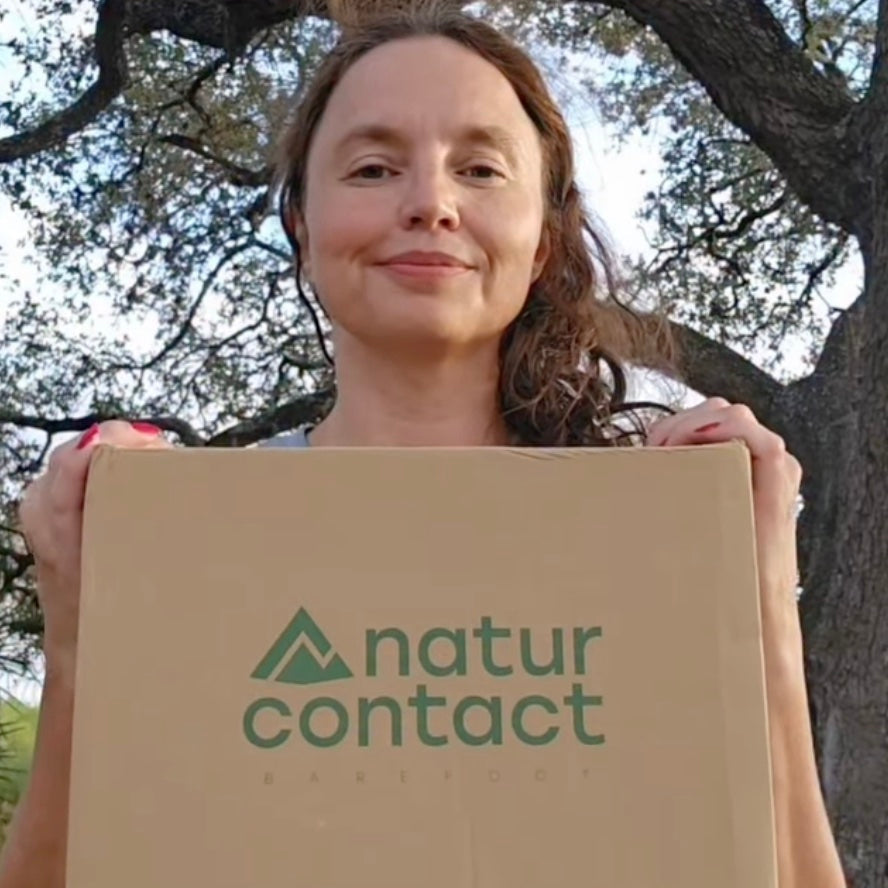 Person holding a box with 'natur contact' logo outdoors