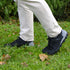 Person wearing black shoes and beige pants standing on grass with a blurred background