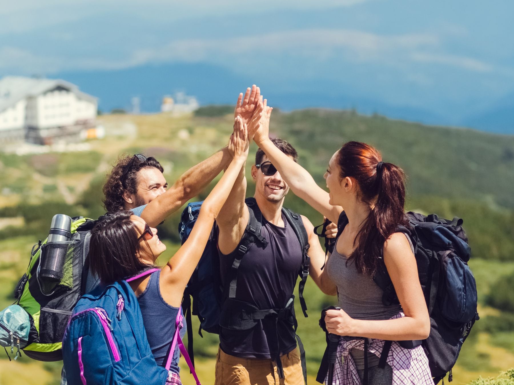 Group of hikers high-fiving on a mountain with scenic background
