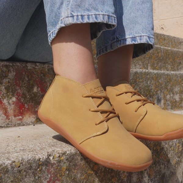 close up of light brown smart barefoot shoes on stairs of a person in jeans sit