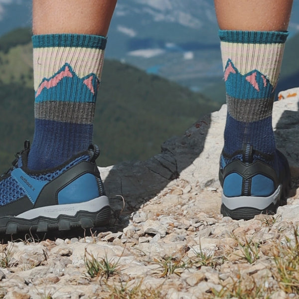 person on mountains wearing blue hiking barefoot shoes and oving them showing flexible movement