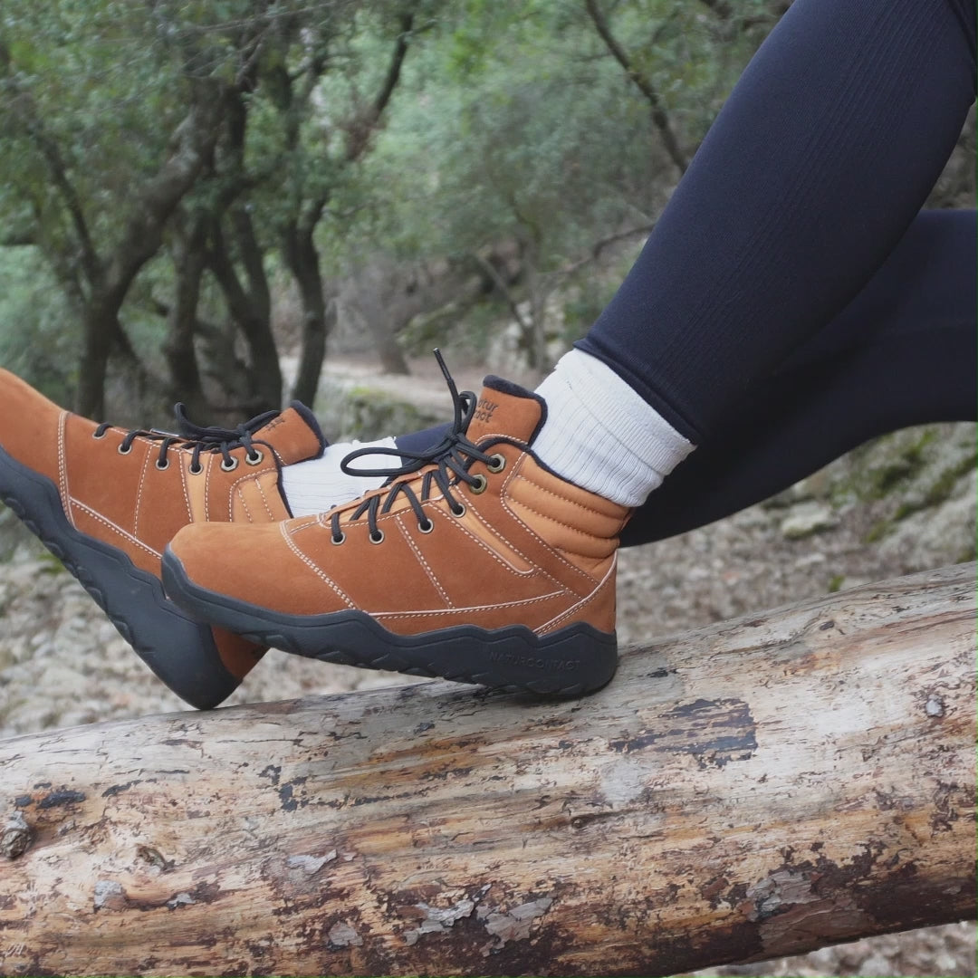 close up of light brown trekking hiking shoes of a person sit in a tree in a forest