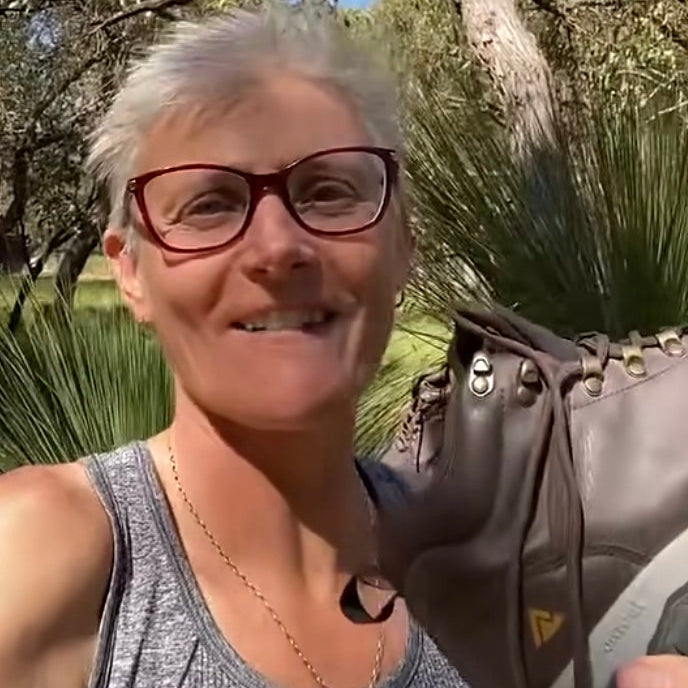 Woman with glasses holding a brown leather bag outdoors