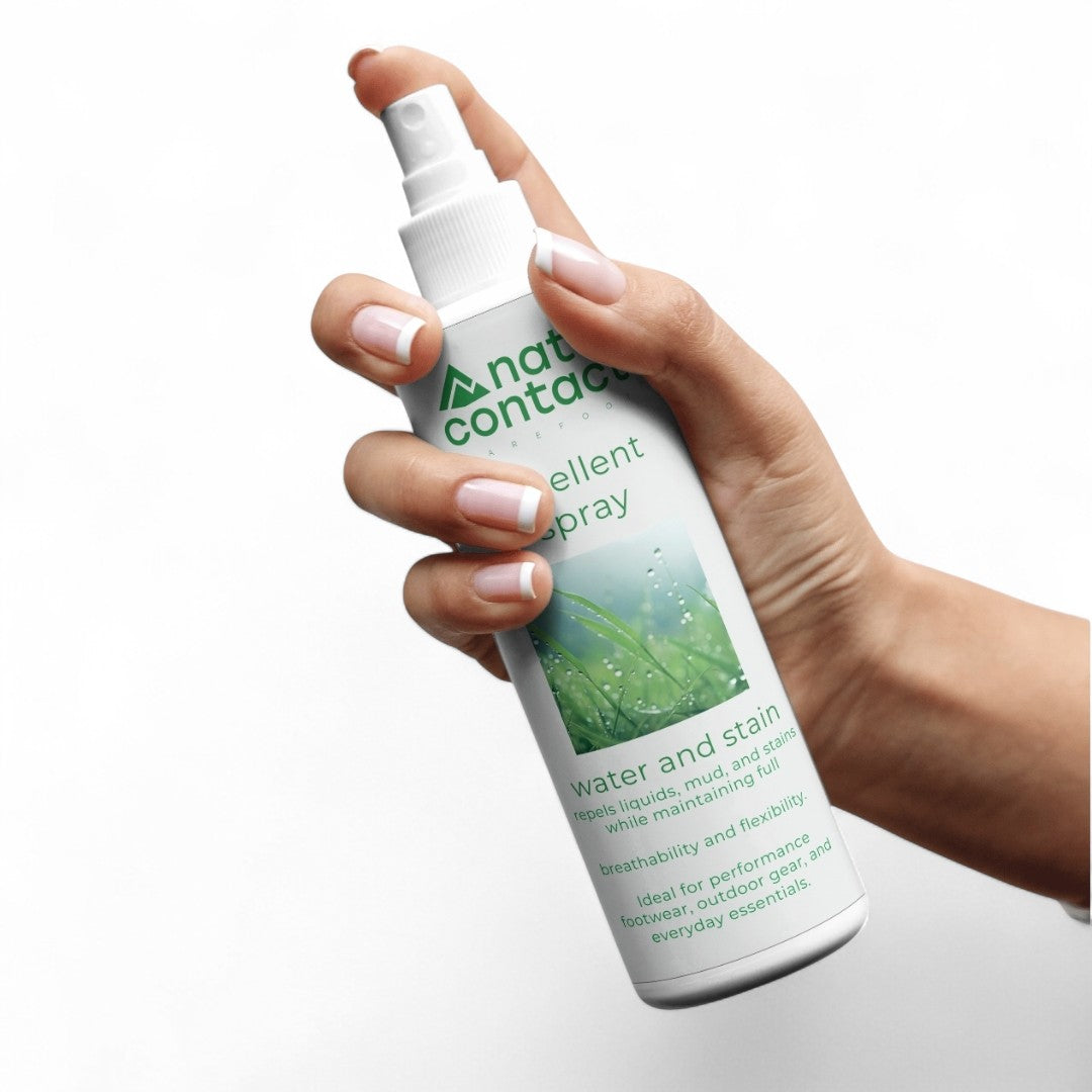 Hand holding a bottle of naturcontact spray water and stain repellent spray on a white background