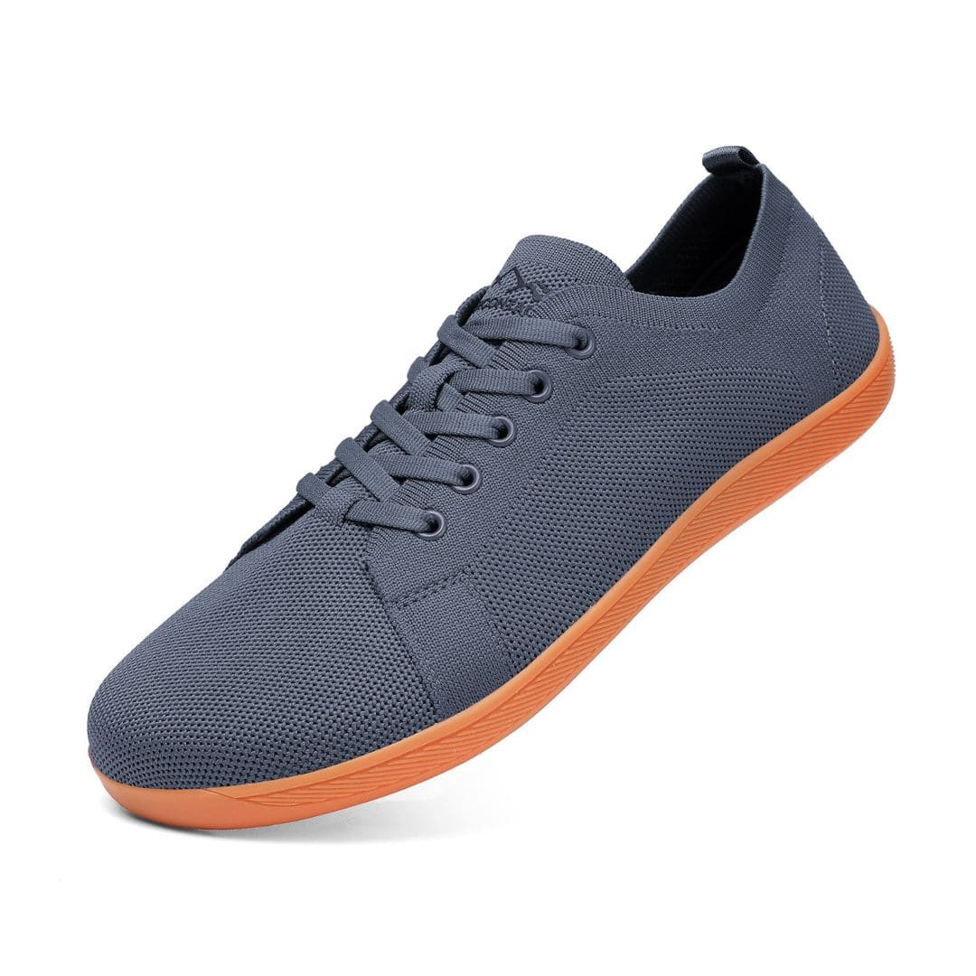 Grey sneaker with orange sole on a white background
