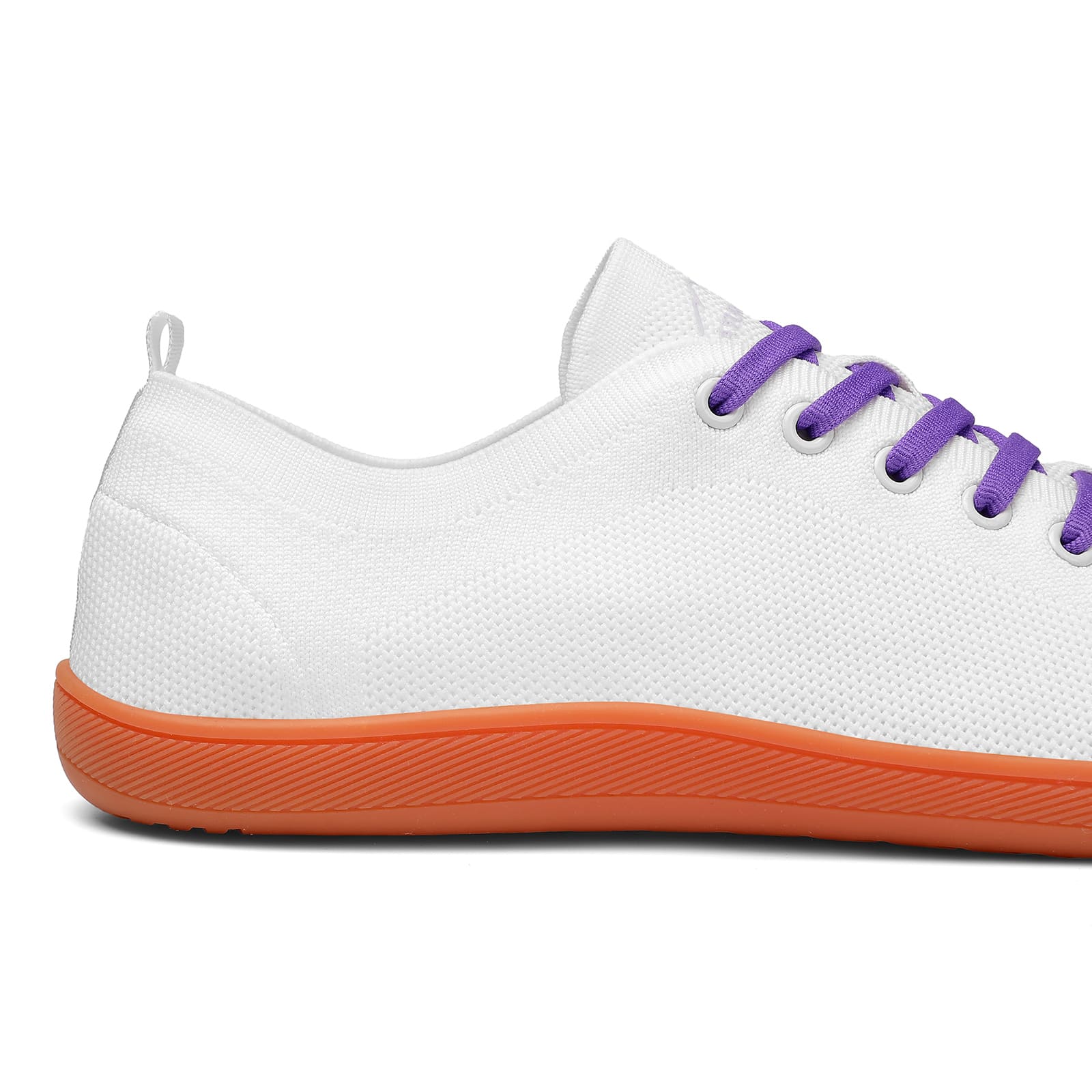 White sneaker with orange sole and purple laces on a white background