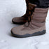 Side view of brown Naturcontact winter boots on snow, highlighting the brand logo on the sole and the layered padded structure