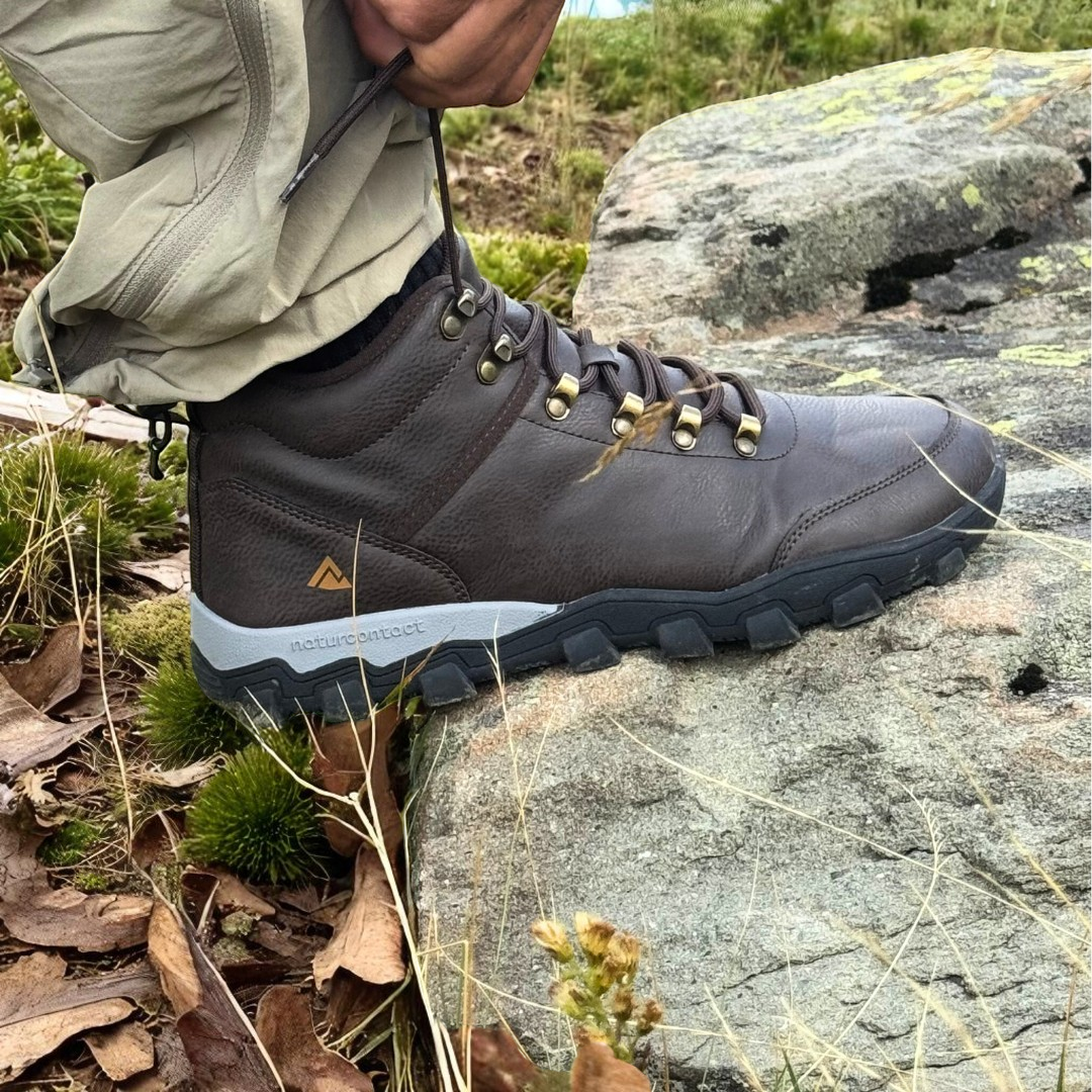 Person wearing a hiking boot on a rocky terrain